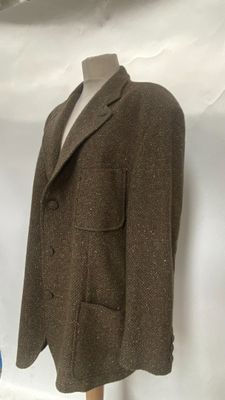 a suit on a mannequin stand in front of a white wall