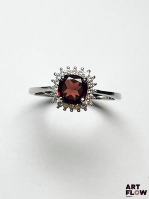gros plan d'une bague avec une pierre rouge entourée de diamants blancs