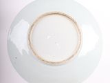 a white plate with a gold rim on a stand