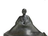 statue of a man sitting on a large piece of metal