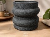 un gros plan d'une jardinière posée sur une table, avec une plante en arrière-plan