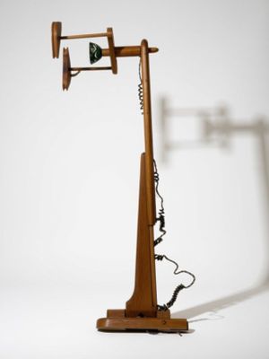 une lampe en bois posée sur un pied, à laquelle est fixé un téléphone
