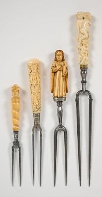 quatre fourchettes ornées de figures sculptées sont alignées sur un fond blanc