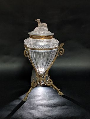 an antique silver and glass covered jar with a bird on top