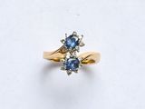 une photo d'une bague sertie d'un diamant et d'un saphir sur un fond blanc