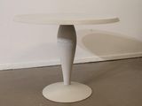 a white table with a white base on the floor