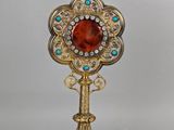 un miroir plaqué or orné d'une pierre rouge entourée de pierres bleues