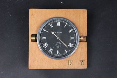 une horloge posée sur un bloc de bois, avec des chiffres romains