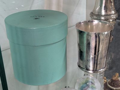 a blue box sitting on a glass shelf next to a silver cup