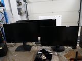 two computer monitors sitting on a table in a garage