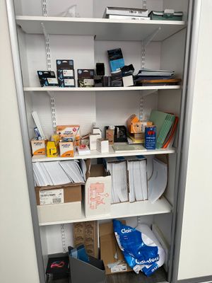 un placard rempli d'objets et un ordinateur portable posé par terre