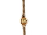 une montre en or sur fond blanc, entourée d'une chaîne