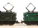 two green trains sitting side by side on a wooden table
