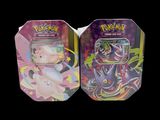 two tins of pokemon cards are sitting side by side on a black background