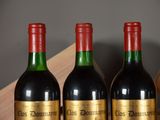 three bottles of red wine are lined up on a shelf