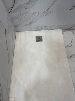 a shower in a bathroom with marble walls and flooring