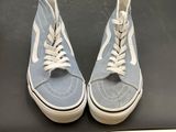 pair of blue and white sneakers with white laces on a black surface
