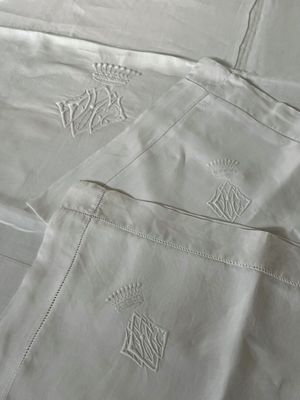 un drap blanc orné de motifs brodés, posé sur un lit