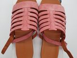 une paire de sandales roses posée sur une boîte blanche
