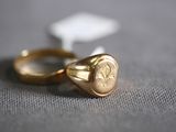 two gold rings with a wax seal sitting on top of each other