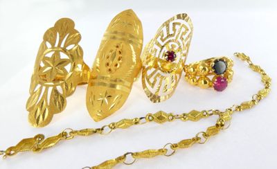 a gold necklace and a pair of earrings on a white surface