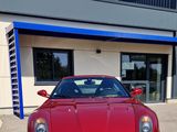 a red ferrari parked in front of a building in front of a blue and white building