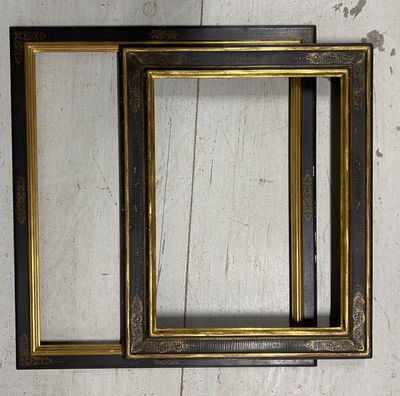 two black and gold picture frames hanging on a wall next to each other
