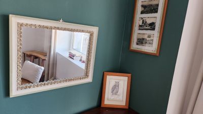 une photo d'un coin de pièce avec un miroir accroché au mur et des tableaux accrochés au mur