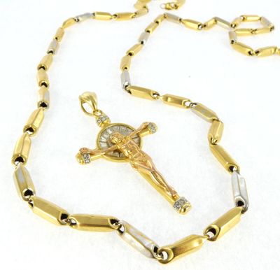 a close up of a cross on a chain on a white surface