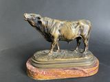 bronze statue of a bull on a marble base on a black background