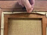 a hand that is holding a piece of wood near a picture