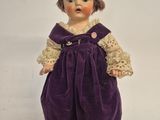 a close up of a small doll on a white surface