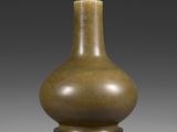 un vase brun posé sur un support en bois sur une surface grise