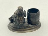 a figurine of a man with a cup on a plate