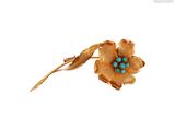 une photo d'une broche en forme de fleur ornée de pierres turquoise