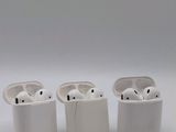 trois AirPods posés les uns à côté des autres sur une surface blanche