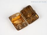 a small metal box with coins in it on a white surface