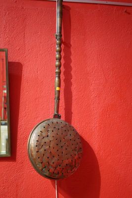 a red wall with a metal strainer hanging from it ' s side
