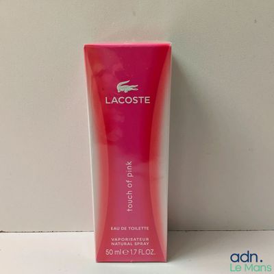 une lotion pour le corps Lacoste dans une boîte rose posée sur une surface blanche