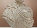 white marble bust of a man with a cape around his neck