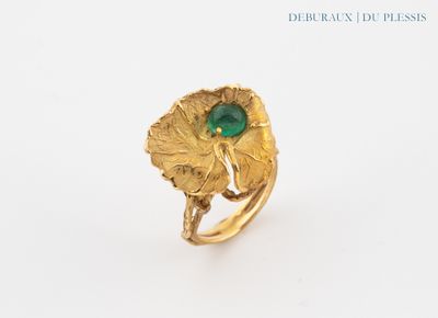 an image of a gold ring with a green stone surrounded by leaves