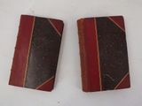 two old books sitting on a table with a white background