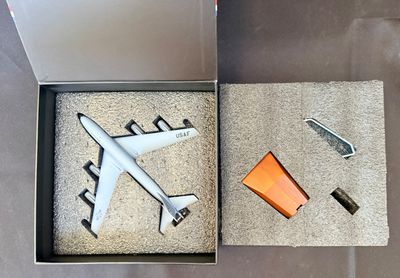 une boîte posée par terre, contenant une maquette d'avion
