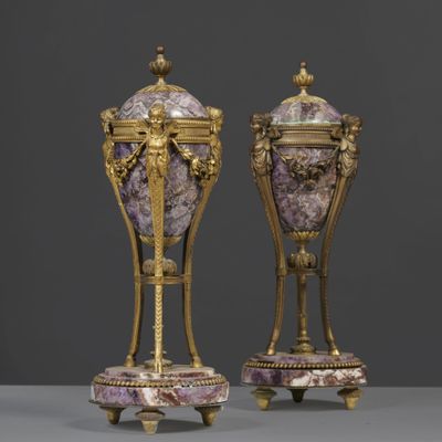 a pair of vases on stands with purple and gold decoration