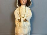 une poupée ancienne représentant une femme en robe blanche et coiffe