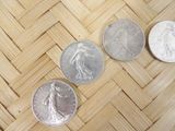 three quarters of silver and silver coins sitting on a woven surface