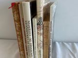 several books are stacked on top of each other on a bed