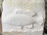 une sculpture en pierre représentant un poisson assis sur un banc