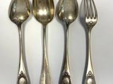 quatre cuillères et une fourchette en argent sur une surface blanche