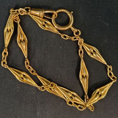gros plan d'un bracelet en chaîne en or sur une surface noire